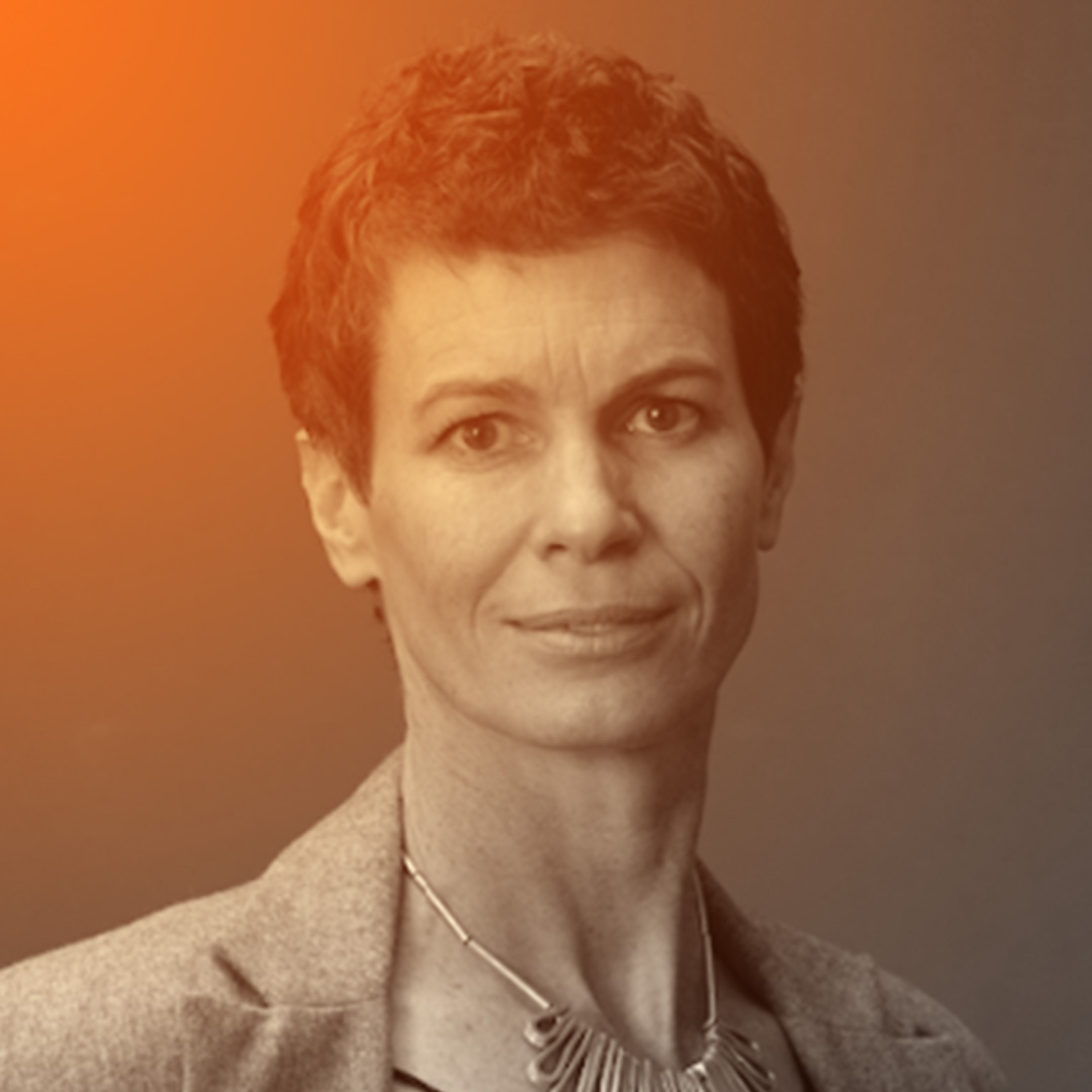 A tall slender white woman in my 50s, wearing my work jacket and black top smiling at the camera.